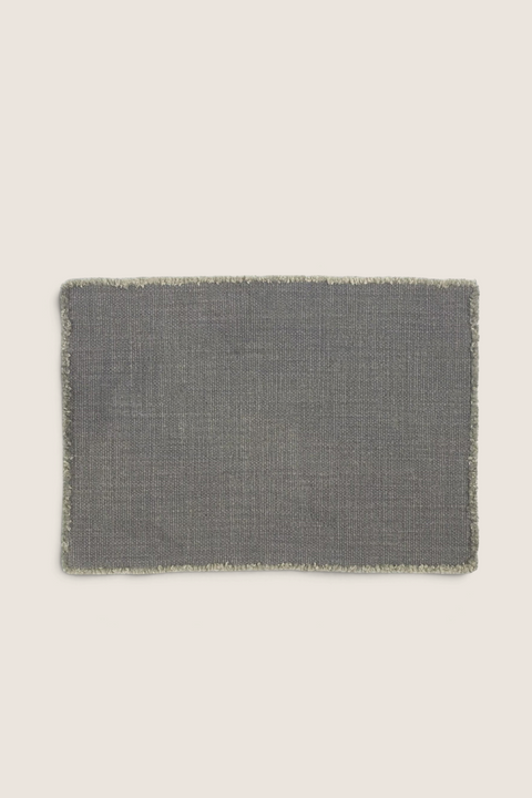 Bolina Jasper placemat in faded black linen with a textured weave and raw fringed edges.