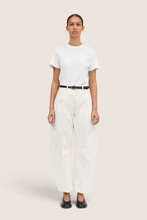 Model wearing Bolina Pella ivory denim jeans with a high waist, loose barrel leg fit, and a thin brown belt.