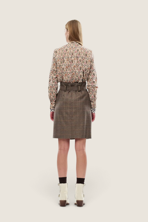 Bolina Nelle Shirt Marlow med blomstermønster i jordtoner, kombinert med et brunt rutete skjørt og hvite støvletter.