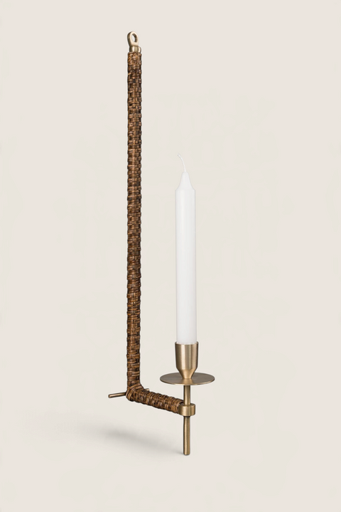 Bolina ERNST wall candle holder in brass and braided seagrass with a white taper candle against a white background.