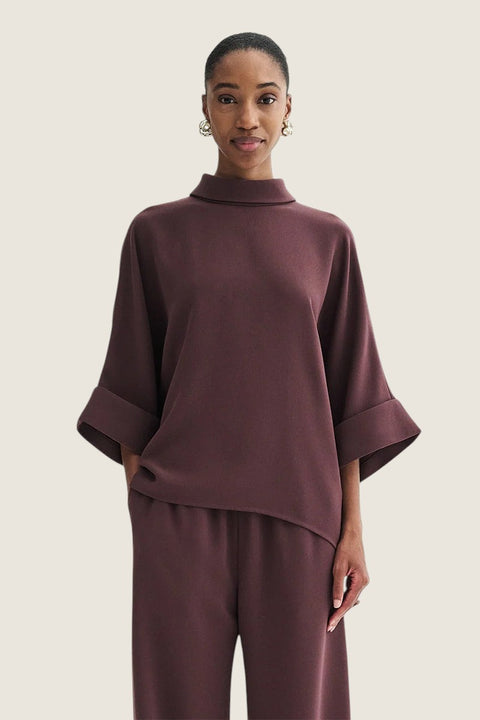 Bolina Bailee burgundy crepe georgette blouse with a loose fit, high neckline, and wide sleeves on a model.