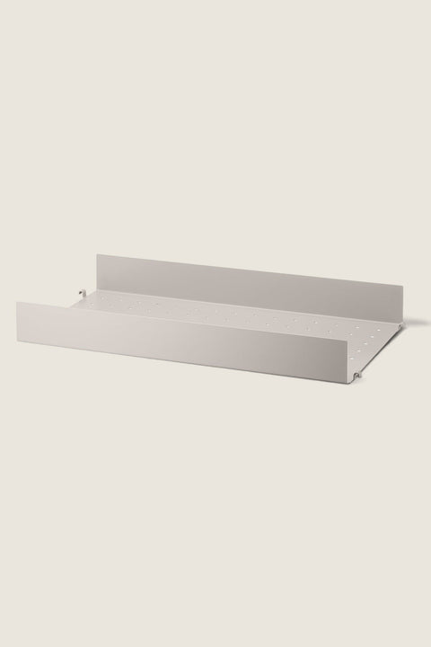 Bolina beige powder-coated steel shelf with a high edge and perforated surface for String System shelving units.