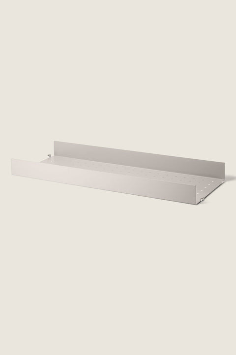 Bolina beige powder-coated steel shelf with high edges and perforated surface for String System shelving