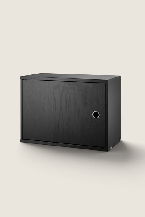 Bolina black ash veneer cabinet with a hinged door for the String System, featuring a minimalist design.