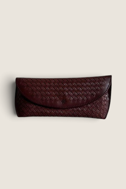 Bolina bordeaux woven leather glasses case with a classic flap closure and artisanal braided texture.
