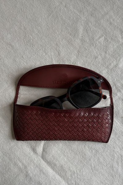 Bolina bordeaux woven leather glasses case with a classic handcrafted design holding dark tortoise shell sunglasses.