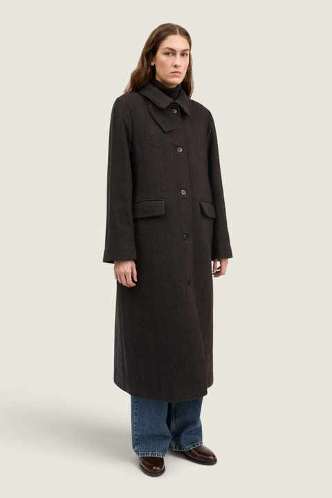 Model wearing a Bolina brown wool Ernest coat with a large collar, button closure, and flap pockets.
