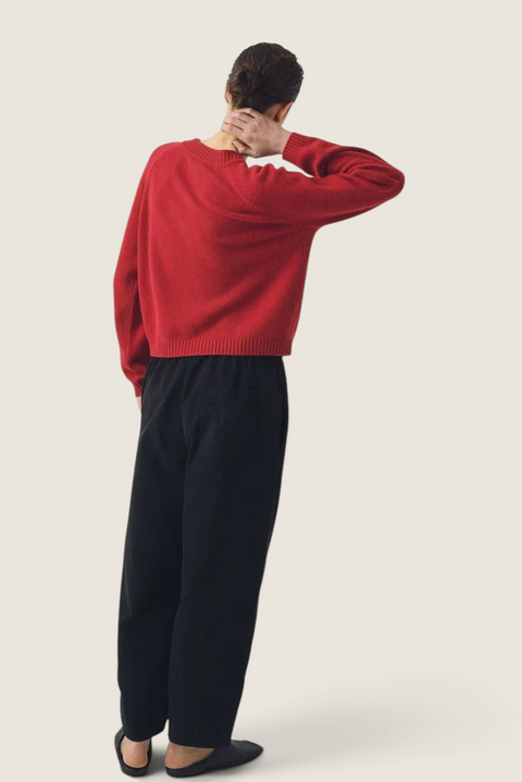 Bolina Eden raglan cardigan in cardinal red merino wool and cashmere blend, worn from the back with black trousers.