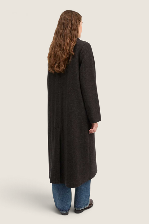 Bolina Ernest wool coat in brown herringbone with a long, relaxed fit and back vent, worn by a model from behind.