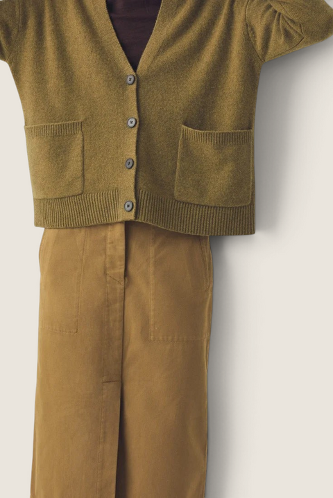 Bolina Ffion boxy cardigan in golden pear wool cashmere blend with V-neck and front pockets worn over a brown skirt.