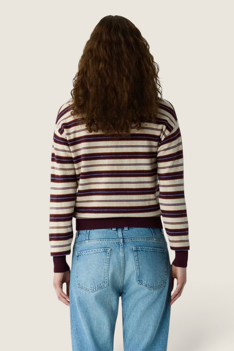 Back view of a Bolina Guest in Residence striped cashmere polo sweater in Fig Combo worn with blue jeans.