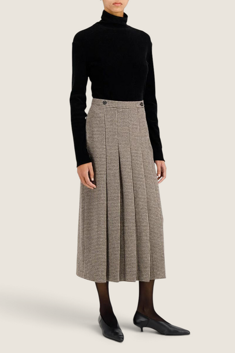 Bolina Harris Wharf London long beige houndstooth moleskin pleated skirt with front slit worn with black turtleneck.