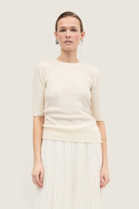 Bolina Kami short-sleeved ivory cashmere knit top with a round neck and slim fit worn with a pleated skirt.