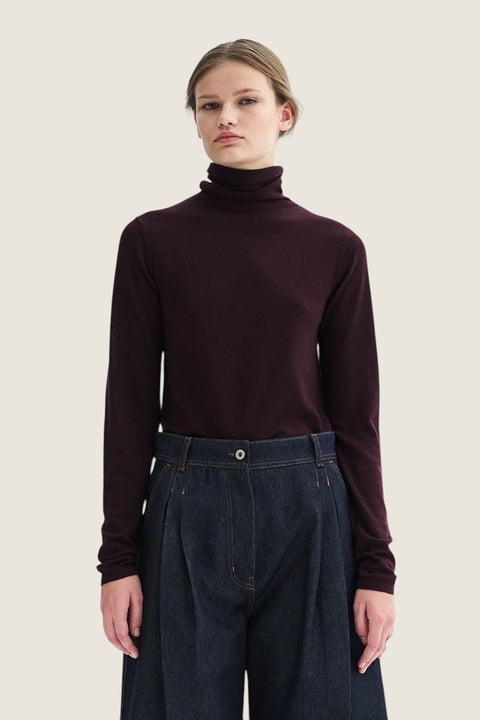 Bolina Korinella merino wool turtleneck sweater in deep burgundy with a slim fit, worn with dark denim trousers.