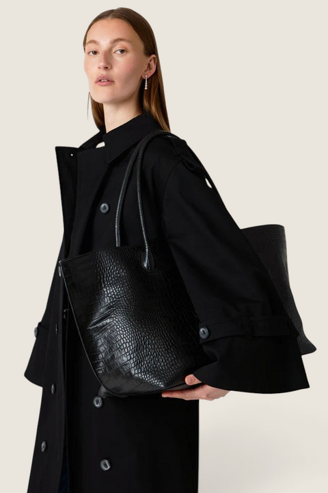 Bolina LIÉ STUDIO Eva weekend tote in black croc-embossed leather carried over the shoulder by a model.