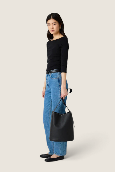 Bolina model wearing a black LIÉ STUDIO Norma leather bucket tote bag with an adjustable strap