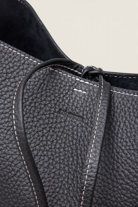 Bolina LIÉ STUDIO Norma Tote in black pebbled leather with white contrast stitching and adjustable drawstring detail.