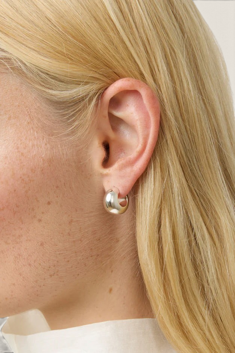 Bolina LIÉ STUDIO The Simone silver hoop earrings with a polished, rounded, and chunky design worn on an ear.