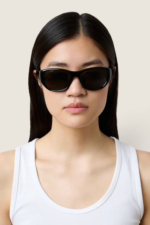 Bolina LIÉ STUDIO The Lee black oversized round sunglasses worn by a woman with a white tank top
