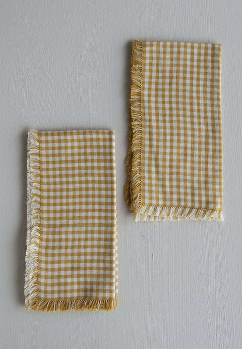 Bolina mustard and white small gingham cotton napkins with decorative fringed edges on a neutral background