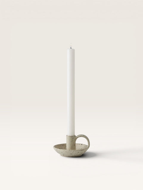 Bolina Nimo beige glazed stoneware candlestick with a small dish and handle, holding a white taper candle.