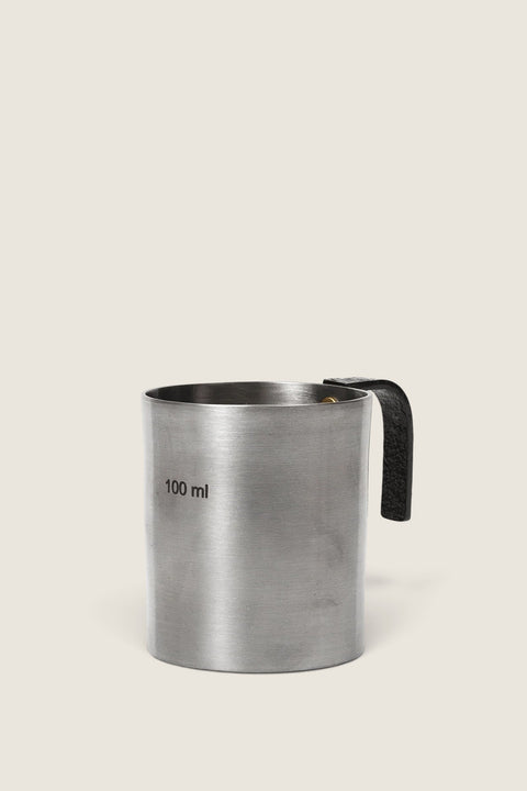 Bolina Obra 100ml measuring cup in brushed stainless steel with a black textured handle and brass rivets.