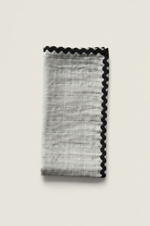 Bolina off-white cotton napkin featuring a decorative dark green ric rac wavy trim edge for a playful table setting.