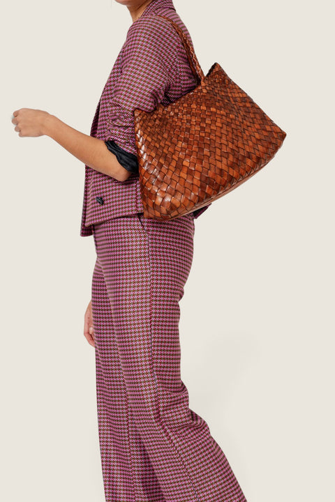 Bolina Santa Croce Big tan woven leather tote bag carried on the shoulder by a woman in a patterned suit