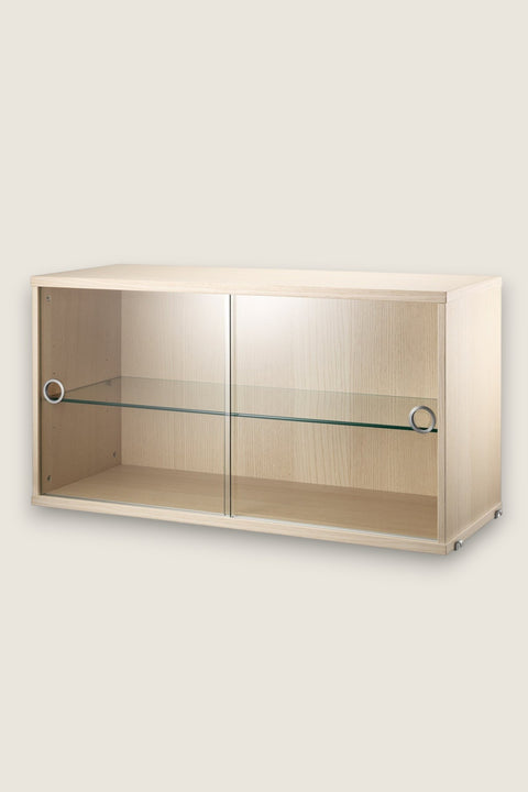 Bolina String System display cabinet in ash wood veneer with sliding glass doors and an internal glass shelf.