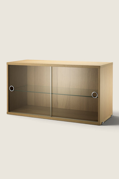 Bolina String System oak display cabinet with sliding glass doors and an adjustable glass shelf.