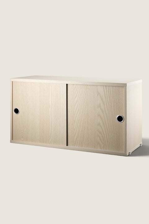 Bolina String System storage cabinet in ash wood veneer with sliding doors and circular metal handles