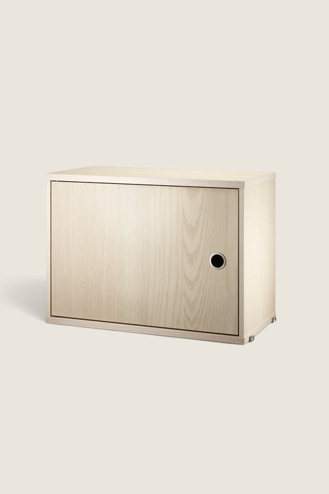 Bolina String System cabinet in light ash wood veneer with a single hinged door and circular handle