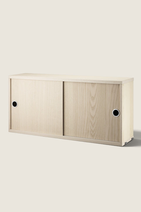 Bolina String System cabinet in ash wood with sliding doors and circular handles for modular wall shelving.