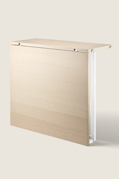Bolina String System folding table in ash wood with white frame, shown in the folded down position.