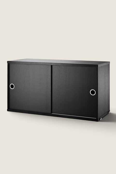 Bolina String System cabinet in black ash veneer with sliding doors and circular handles for modular shelving
