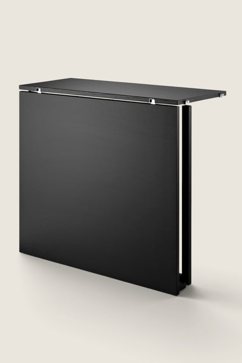 Bolina String System black ash folding table in a folded down position against a white background