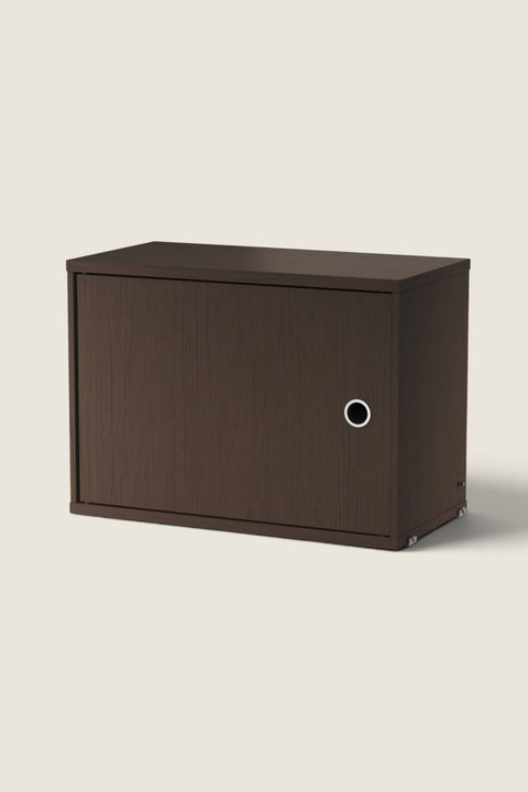 Bolina String System cabinet in dark oak with a single hinged door and circular handle for modular shelving.