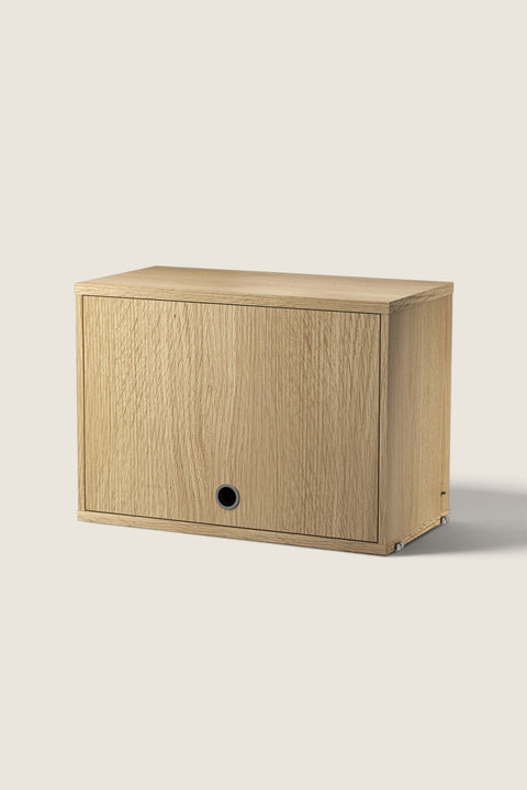 Bolina String System flip door cabinet in oak veneer with a minimalist design and a circular handle