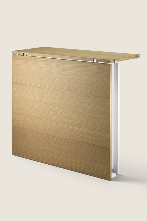 Bolina String System foldable oak table in a folded position, showing wood grain finish and white side support.