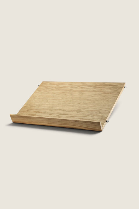 Bolina String System oak magazine shelf for 30cm deep panels, featuring a slanted design for display.