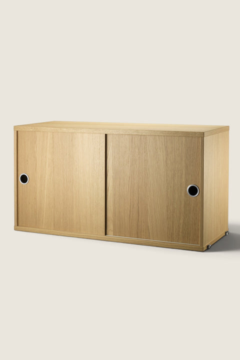 Bolina String System oak cabinet with sliding doors, featuring a clean minimalist design for modular wall shelving.