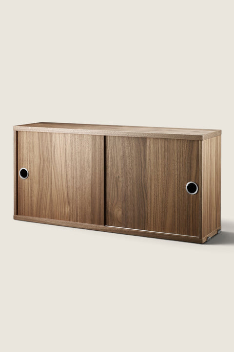 Bolina String System walnut cabinet with sliding doors and circular silver handles for modular wall shelving.