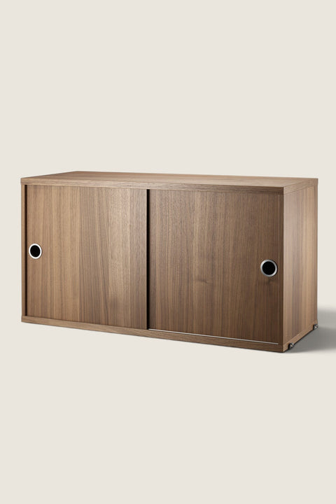 Bolina String System walnut cabinet with sliding doors and circular silver handles for modular shelving storage