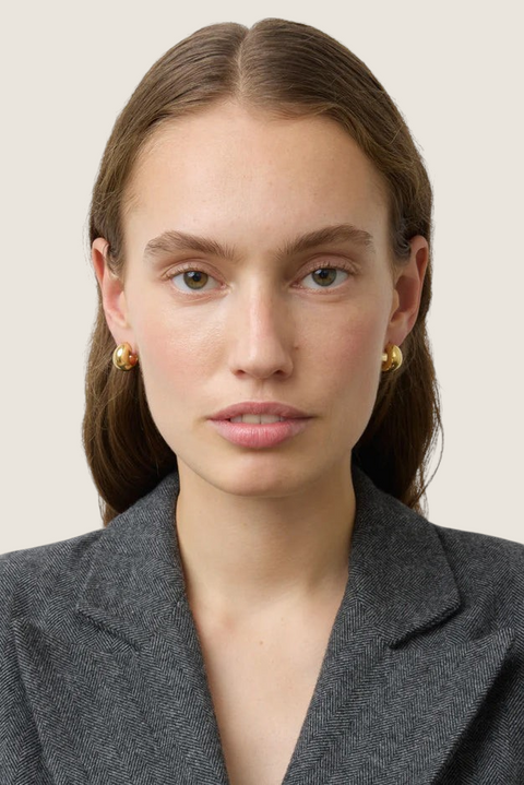 Bolina The Simone gold hoop earrings worn by a model, featuring a polished, rounded, and chunky design.