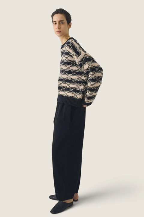 Model wearing a Bolina TOAST navy and ecru jacquard striped wool sweater with dropped shoulders and ribbed edges.