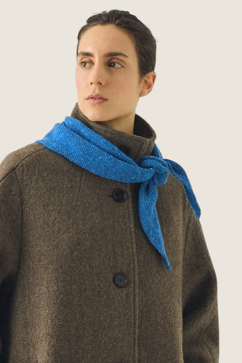 Bolina TOAST porcelain blue Donegal merino wool bandana scarf tied around a model's neck over a brown wool coat.