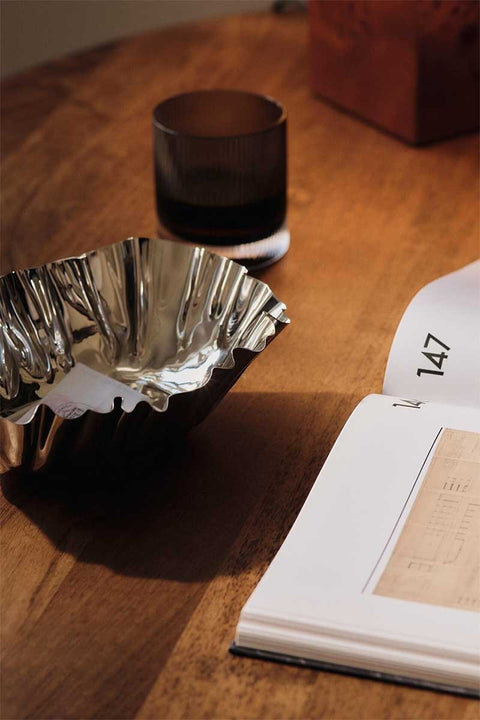 Bolina Ferm Living Tydra bowl in mirror polished stainless steel with a wavy design on a wooden table