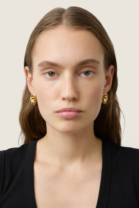 Bolina Vera gold knot-style sculptural earrings worn by a model, featuring a polished finish and close-ear fit.