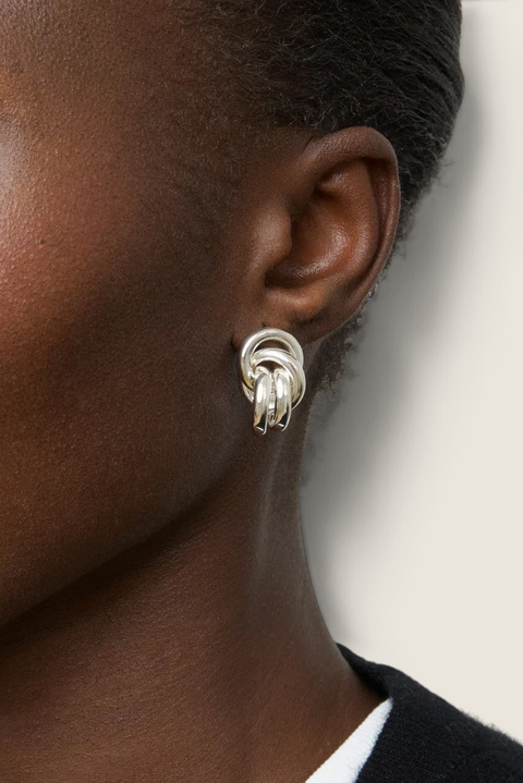 Bolina Vera silver knot-style sculptural earrings worn on a model, featuring a polished metallic finish.