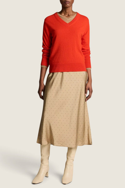 Bolina Vince crimson red fine-knit cashmere V-neck sweater worn with a beige polka dot midi skirt and cream boots